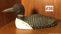 Front angled view of the wooden loon carving showing the detailed spot painting and red eye with black beak.