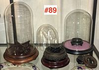 Front view of glass domes on wooden bases and multiple Asian-style wooden stands and risers for displaying collectibles.