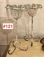 Pair of white metal patio planters with rustic shabby chic paint loss and crystal-like hanging decorations, standing 21 inches tall on twisted metal stems and scroll feet.