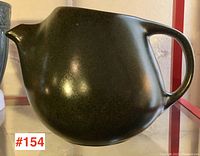 Front view of a dark green Roseville pottery pitcher showing the body shape, spout, and handle details.