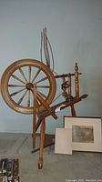 Wooden spinning wheel assembled, showing eight-spoke wheel, treadle, flyer, and warp tension posts.