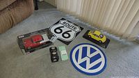 All collectibles including four model cars and two signs arranged on floor.