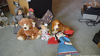 Full lot including two dog doorstops, three stuffed animals, and two rag dolls on carpeted floor