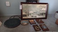 Framed GH Durrie winter scene print and assorted wall art including ceramic Aztec calendar and metal plate on carpeted floor