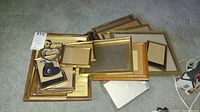 Fifteen assorted small picture frames stacked showing variety in sizes and materials including wood and metal