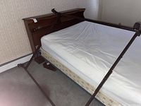 Side view showing pine wood headboard with divided bookshelf and one metal adjustable bed frame attached to mattress base