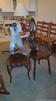 Pair of two vintage wooden chairs with different carved back designs shown in living/dining room area.