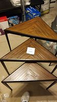 Three nested triangle nesting tables showing wood patterned tops with metal frames.