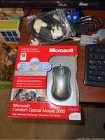 Microsoft Comfort Optical Mouse 3000 in package with accessories and part of keyboard visible