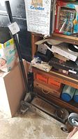 Floor jack in garage surrounded by other household and storage items, showing complete jack with handle upright.