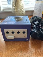 Front view of purple Nintendo GameCube console with four controller ports and power adapter cable