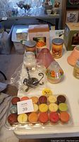 Photo showing assorted candle items including 18 count votive sampler, 2 large jar candles in Sun & Sands and Mango Peach scents, and Elements candle crock and warmer.