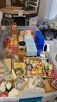 Overview of the lot showing various candles in bins including boxed candles and votives.