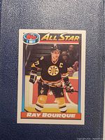 Front side of the Topps All Star Ray Bourque hockey card showing player in Boston Bruins uniform, with All Star banner at top and player name on bottom.