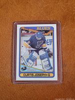 Front view of Curtis Joseph rookie card showing player in St. Louis Blues goalie gear, card in protective casing.