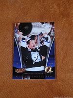 Front photo of Dave Andreychuk holding Stanley Cup, black jersey, gold foil name and logos