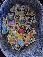 Top view of a large quantity of Pokémon trading cards loosely arranged in a container showing a wide assortment of cards.