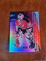 Holographic front of Martin Brodeur NHL hockey card in New Jersey Devils goalie uniform with 'Heroes' title and holographic foil shine.