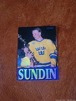 Front of the Mats Sundin hockey rookie card showing the image of Sundin in the Swedish national jersey holding a trophy. The card has the Globe logo and large "SUNDIN" text.