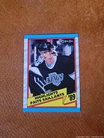 Front view of 1989 Wayne Gretzky hockey card featuring him in a black Los Angeles Kings uniform with helmet, yellow and red Highlights '89 banner, blue border.