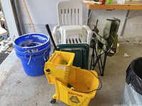 Photo showing white plastic garden chairs, green folding stools, blue dura tubs, yellow mop bucket with wringer, and green folding camping chair.