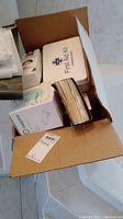 Box with various first aid supplies and kits, including AMB metro protective masks, gauze sponges and other items