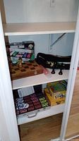 Wood chest containing stacked board games including Shoot a Loop and You're It!, chess pieces in carrying case, and a visible wooden chessboard on top.