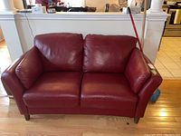 Front view of red leather loveseat showing seat cushions, back cushions, armrests