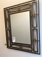 Full view of rectangular mirror with metal frame and decorative circular brass-colored accents around perimeter.