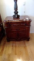 Full front view of wood night stand showing stone top and four drawers with carved wood details