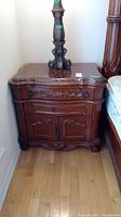 Full front view of night stand showing carved wood base and marble top