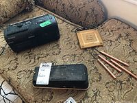Overall view of all items together on patterned couch including Sony cassette-corder, Cry Baby amp pedal, and wind chimes with wooden plaque.
