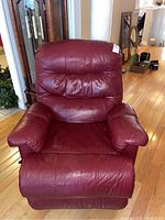 Front view of red leather recliner chair showing cushioned back, seat, and armrests