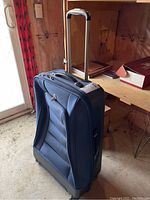 Front and side view of upright black Swiss Gear suitcase with extended handle in basement setting