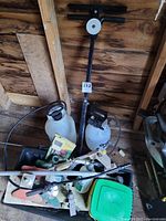 Full view of items showing garden spreader, sprayers, fertilizer box, and garden fittings.