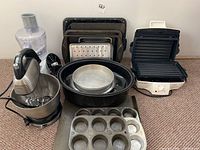 Photo showing entire lot with stand mixer, food processor, grill and assortment of baking pans including muffin tin and cake pans.