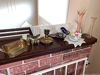 Photo of all items on dark wood shelf including brass tray, candle holder, butterfly brass piece, ceramic floral china, pink vases, and decorative items.