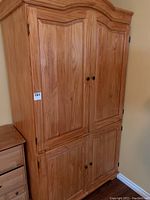 Full view of closed pine cabinet showing wood grain, doors with knobs, and decorative top molding.