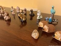 Image showing multiple miniature ceramic animal figurines arranged on a surface, including poodles, hedgehogs, and a turquoise bird missing one eye, alongside a turquoise stone cuff bracelet.