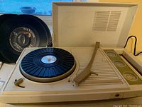 Vintage off-white Sears phonograph turntable with lid open, arm raised missing needle, and RCA Victor record next to it.