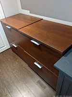 Photo showing top and side view of the two matching wooden filing cabinets with three drawers each, medium brown finish, and silver handles.