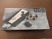 Box of BLKSMITH Boozy Cornhole set showing two boards, six bean bags, and four shot glasses with tagline "You sink it, they drink it."