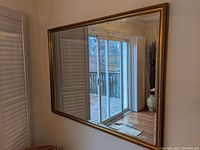 Large rectangular mirror mounted on wall reflecting room interior and sliding doors.