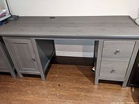 Front view of full desk showing grey wood finish, cabinet door at left, two upper drawers and one lower file drawer at right