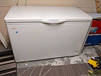 Full front view of white chest freezer on concrete floor
