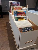 Long white box filled with bagged and boarded comics, viewed at an angle to show depth of contents.