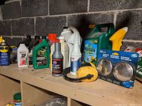 Shelf with assortment of automotive and garden chemicals including oils, lubricants, herbicides, spray paint, and accessories