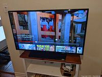 Samsung 42" TV powered on displaying video content on stand atop wooden console