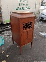 Full view of vintage wooden cabinet with closed doors, showing overall shape, wood grain, and leg details.