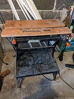 Front view of the work bench showing the wooden clamping surfaces and black metal frame.